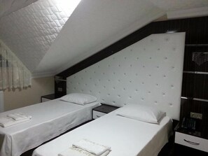 A hotel room with two single beds, a small bedside table, a nightstand, a wardrobe, and a quilted ceiling. - Sener Hotel (Pamukova)