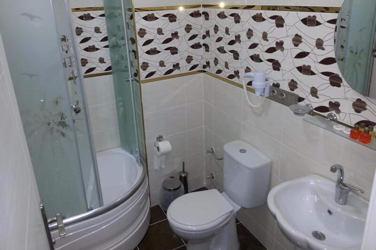 A bathroom with a glass-enclosed shower, a toilet, and a sink.