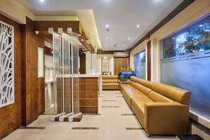 A modern interior with a wooden reception desk, a leather sofa, and a fish tank. - Treebo Amber International Mumbai Airport T2 (Mumbai)