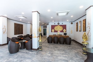 A lobby with a reception desk, seating area, and decorative wall art. - Ratana Hotel (Chiang Mai)
