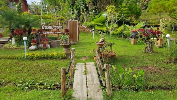 A garden pathway leading to a wooden structure with a sign in a foreign language. - Ban Mae Resort (Khao Kho)