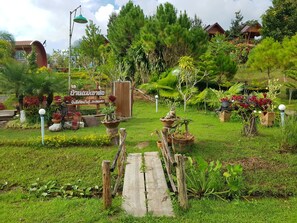 Un sentier de jardin mène à une structure en bois sur laquelle est apposée une enseigne dans une langue étrangère.