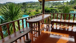 A wooden deck with a bench and a table, overlooking a lush green landscape. - Ban Mae Resort (Khao Kho)