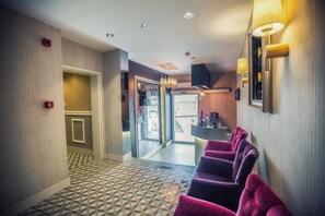 Un vestíbulo de hotel con suelo de estampado geométrico, una recepción y asientos morados.