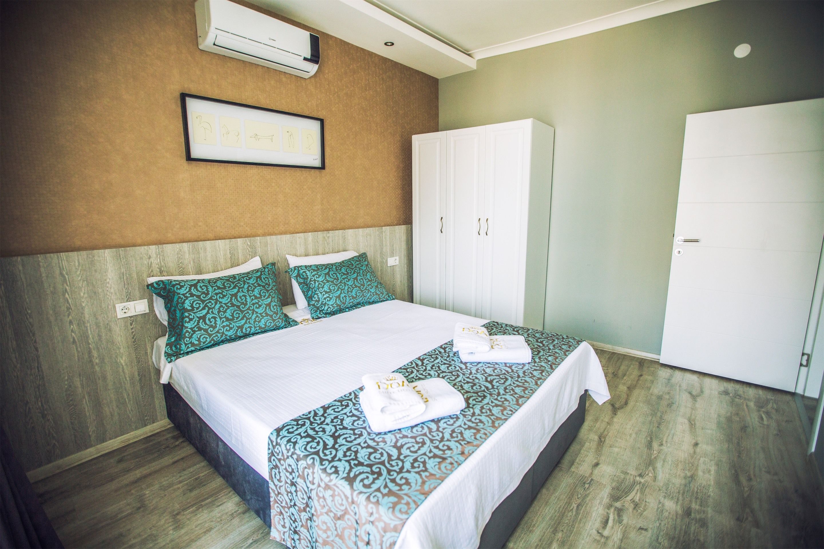 Una cama bien hecha con ropa de cama estampada, un armario y un cuadro en la pared.