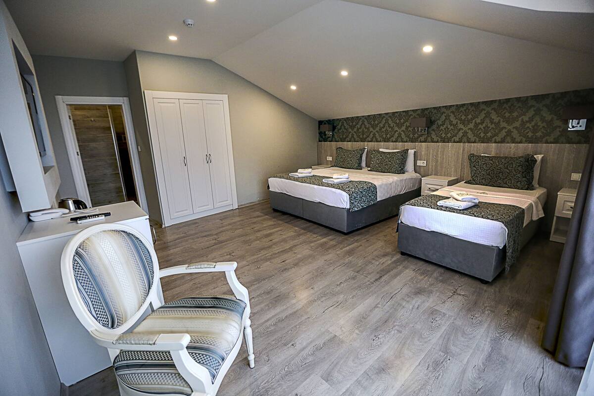 A hotel room with two beds, a desk, a chair, and a wardrobe.