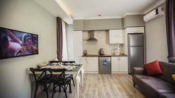 A compact living space with a dining area, kitchenette, and a sofa.