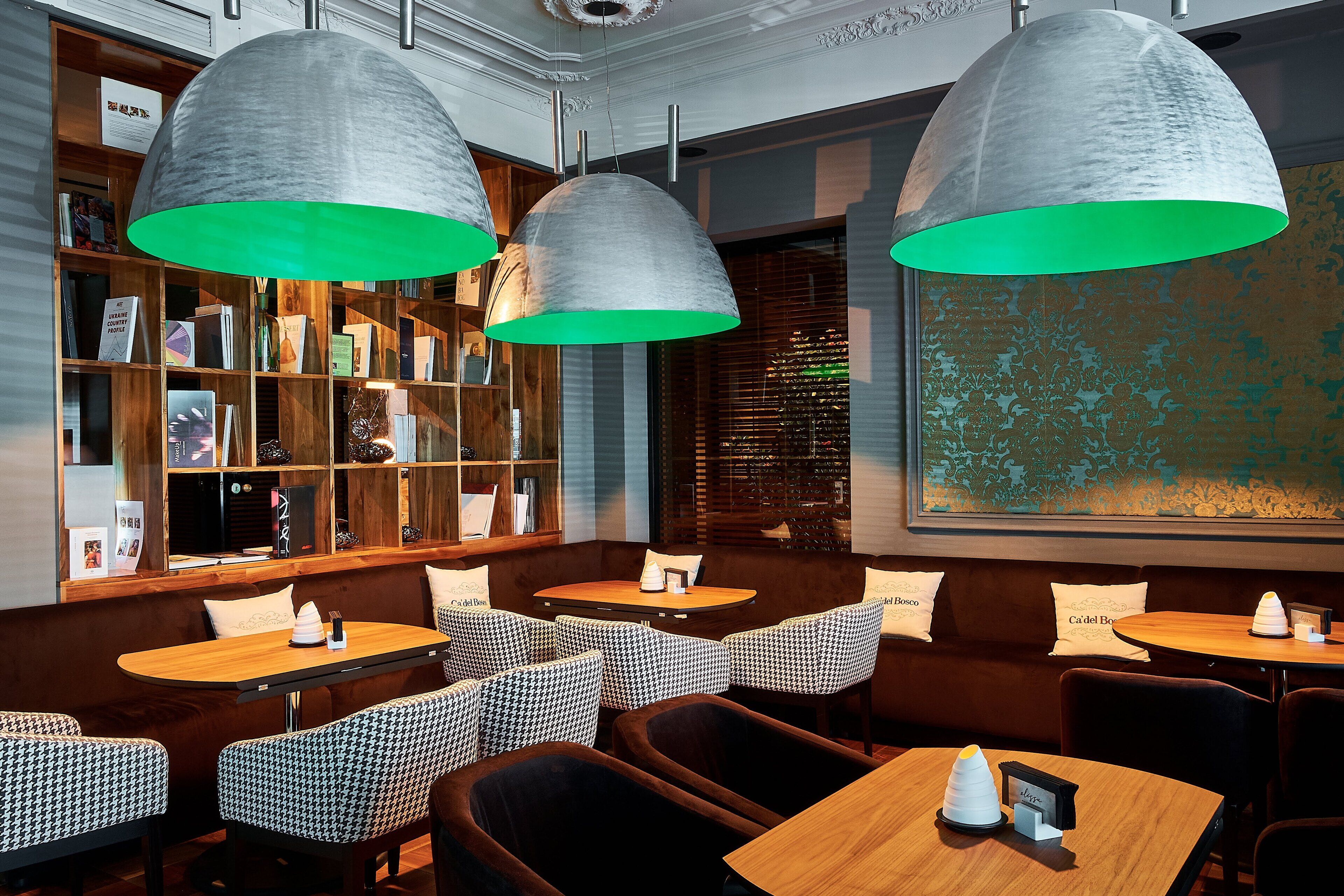 A cozy restaurant interior with wooden bookshelves, patterned seating, and pendant lighting.