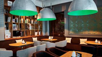 A cozy restaurant interior with wooden bookshelves, patterned seating, and pendant lighting.