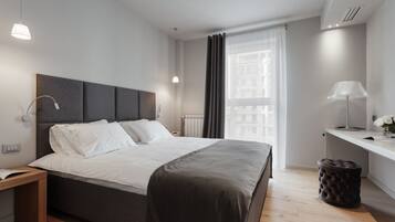 Un dormitorio moderno con una cama grande, mesitas de noche, un escritorio y una ventana con cortinas.