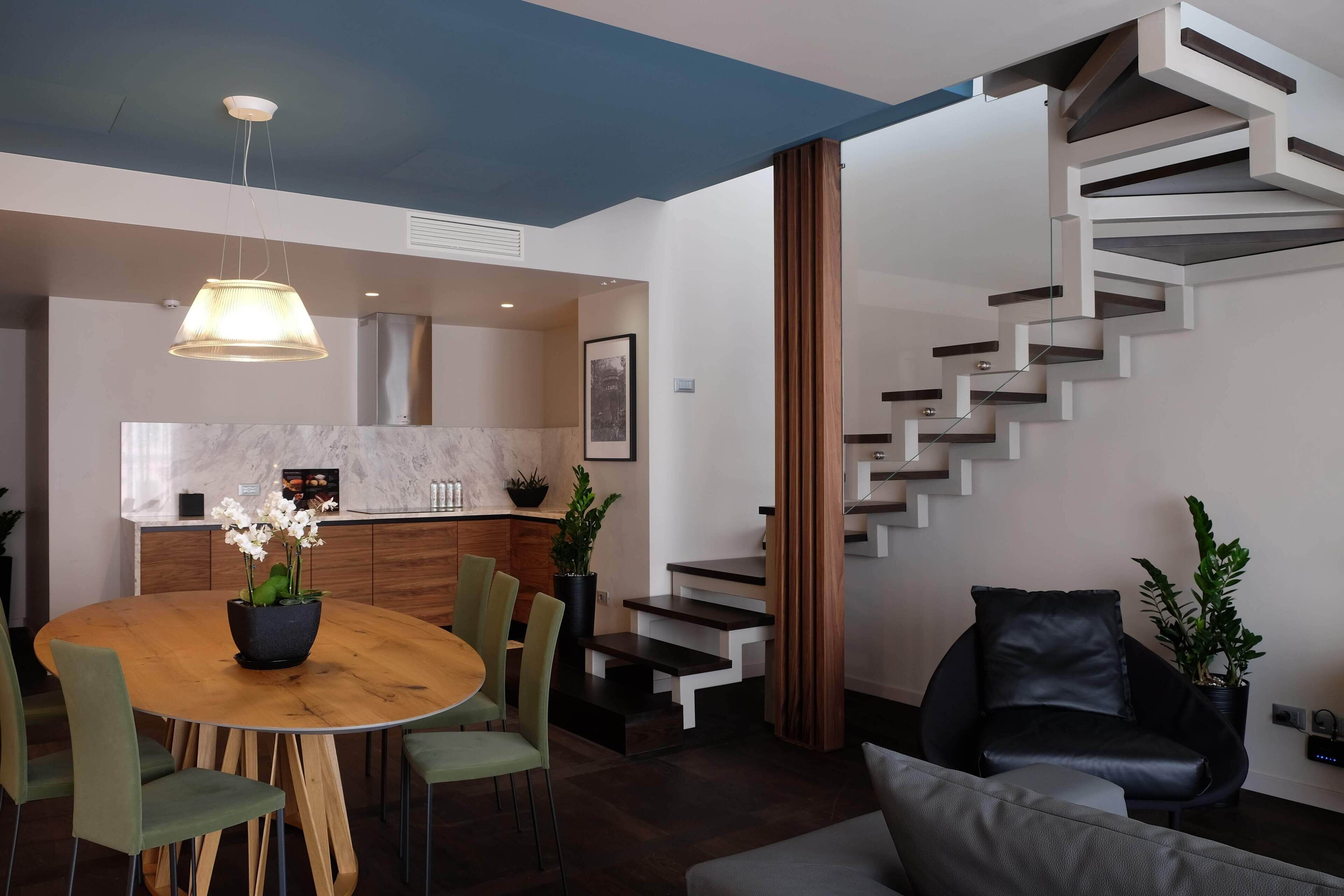A modern living space with a dining area, a staircase, and a kitchen.