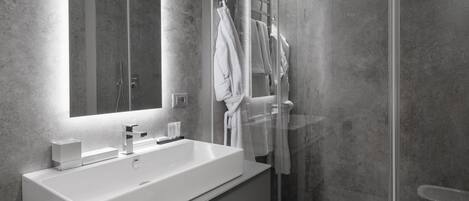 A modern bathroom with a large white sink, a glass shower enclosure, and a mirror above the sink.