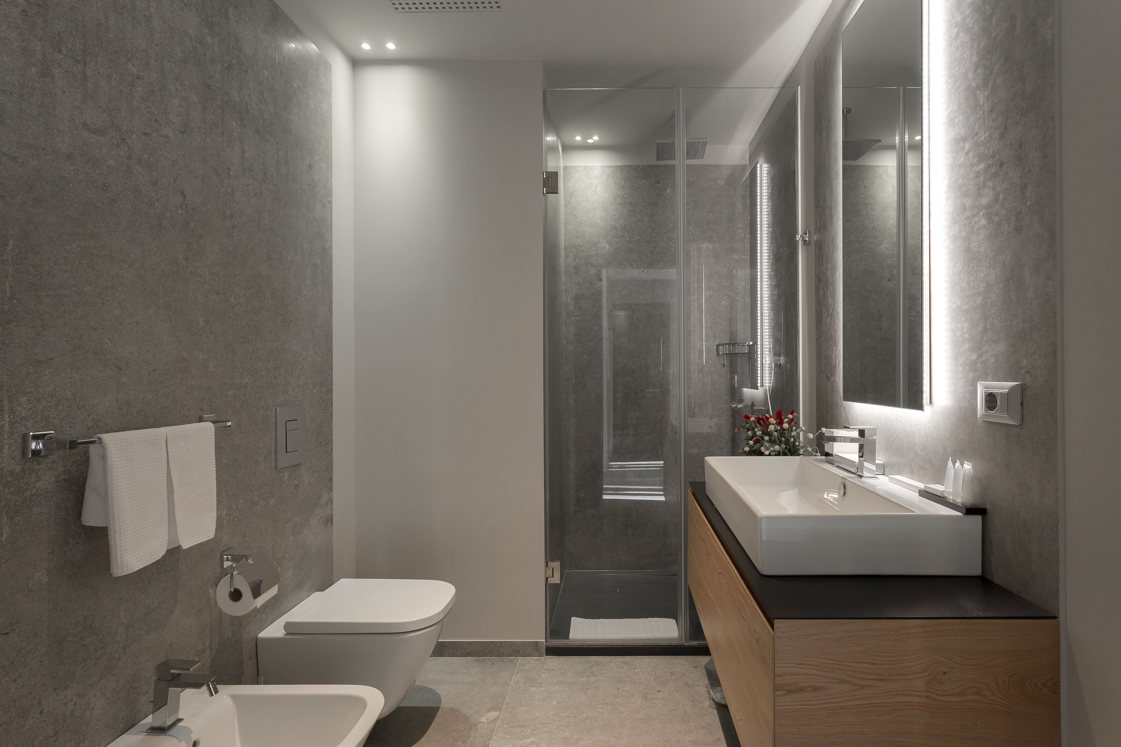 A modern bathroom with a glass shower enclosure, a freestanding bathtub, and a wooden vanity with a large mirror.
