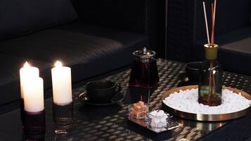 A tray with candles, a teapot, a cup, and a diffuser on a textured table.
