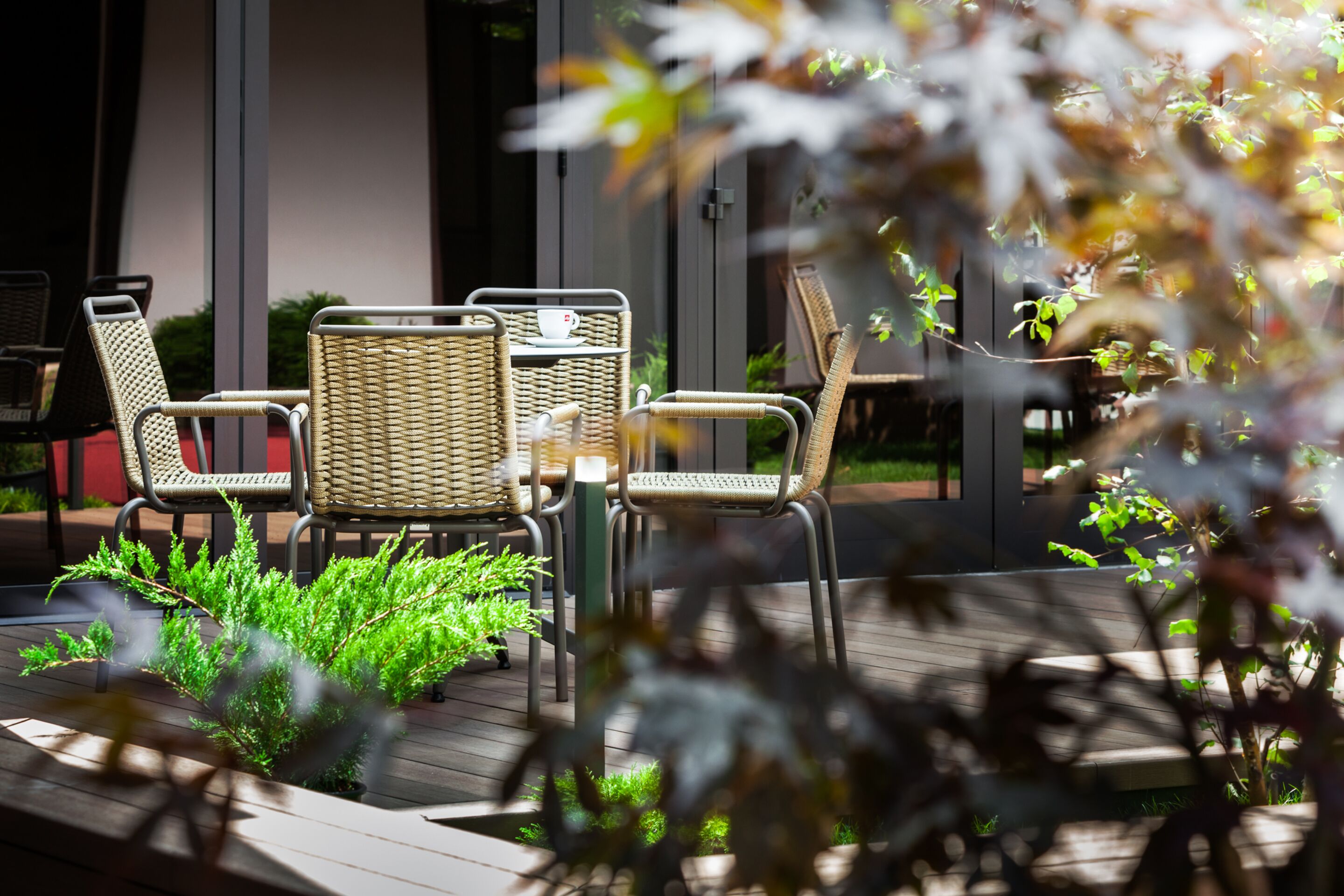 A patio area with wicker furniture and a small table with a cup and saucer.