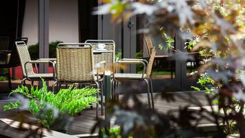 A patio area with wicker furniture and a small table with a cup and saucer.