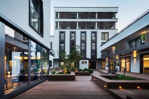 A modern building with multiple floors, large windows, and outdoor seating areas with plants. - Il Decameron Luxury Design Hotel  (Odesa)