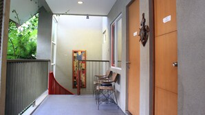 A hallway with a wooden door, a bench, and a red railing. - Buton Backpaker Lodge - Hostel (Bandung)