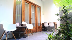 A room with a wooden door, a table with chairs, and a potted plant. - Buton Backpaker Lodge - Hostel (Bandung)