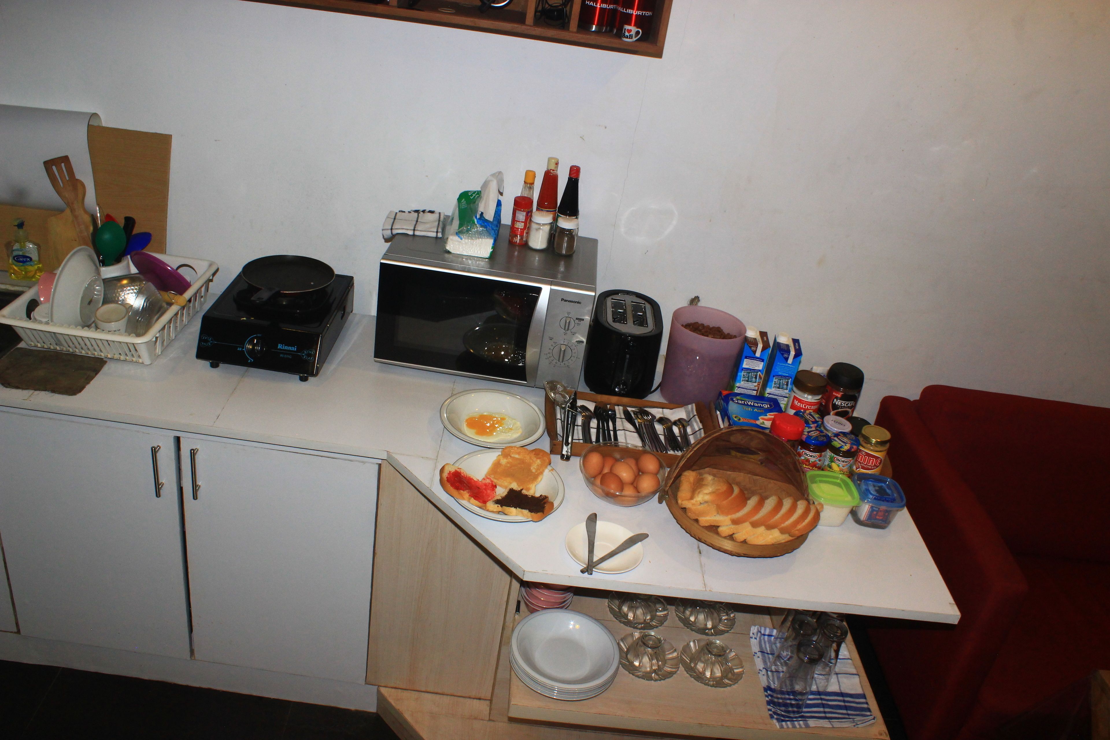 A kitchen counter with various food items, utensils, and appliances like a toaster, microwave, and blender.