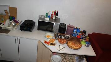 A kitchen counter with various food items, utensils, and appliances like a toaster, microwave, and blender.