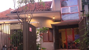 A building with a gated entrance, a sign indicating a backpacker hostel, and a bicycle parked outside. - Buton Backpaker Lodge - Hostel (Bandung)