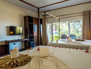 Une chambre d’hôtel équipée d’un lit, d’une télévision, d’un mini-bar et d’une fenêtre donnant sur un paysage verdoyant.