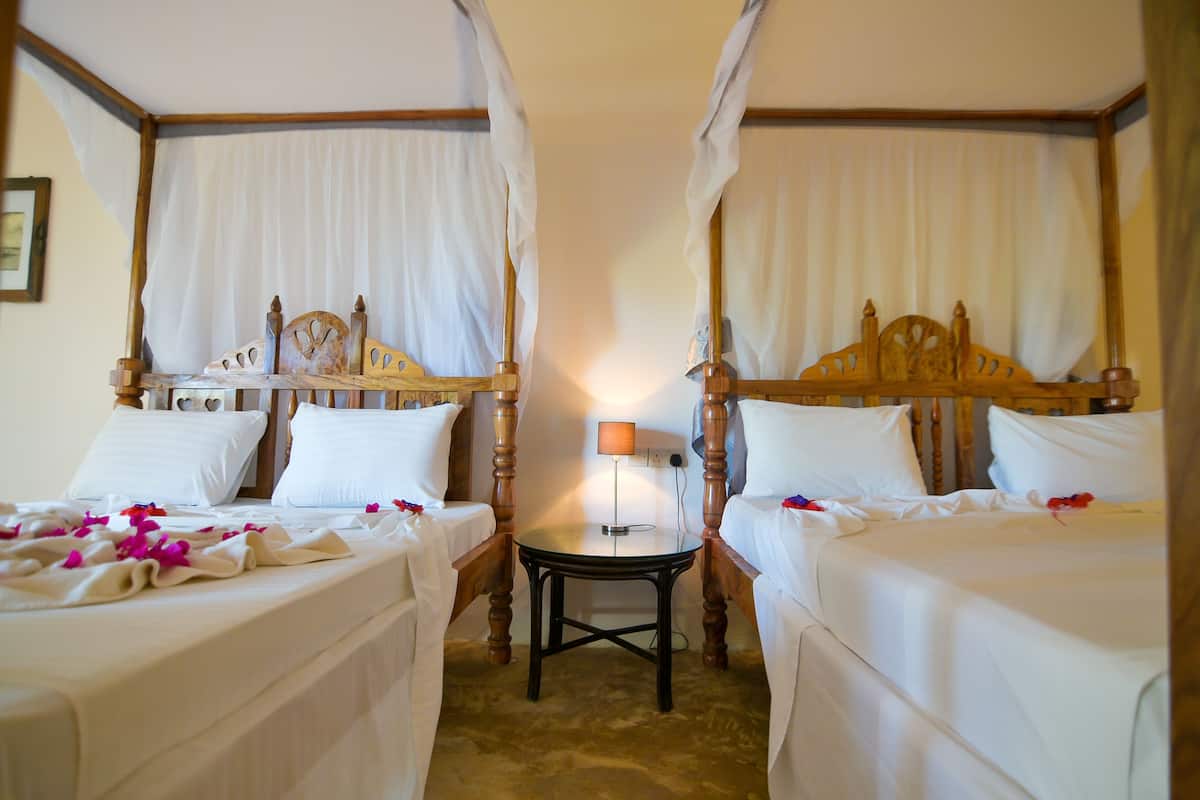 A room with two beds, a small table, and a lamp.