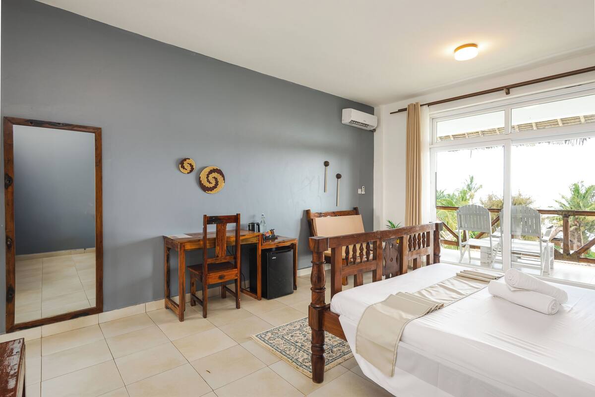 A bedroom with a bed, a desk, a chair, and a small table.