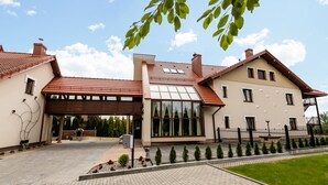 A two-story house with a tiled roof, a covered entrance, and a paved driveway. - Hotel Krzyski (Tarnow)