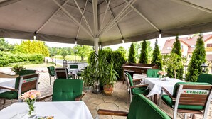 An outdoor patio area with green upholstered chairs and tables, a Heineken-branded chair, and a potted plant. - Hotel Krzyski (Tarnow)