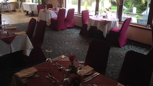 A dining area with tables set for four, each with red chairs and white tablecloths. - The Manor Country House Hotel (Dumfries)