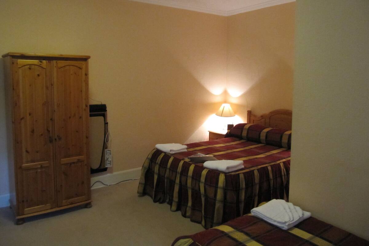 Ein Schlafzimmer mit einem Bett, einem Nachttisch, einer Lampe und einem Holzschrank.
