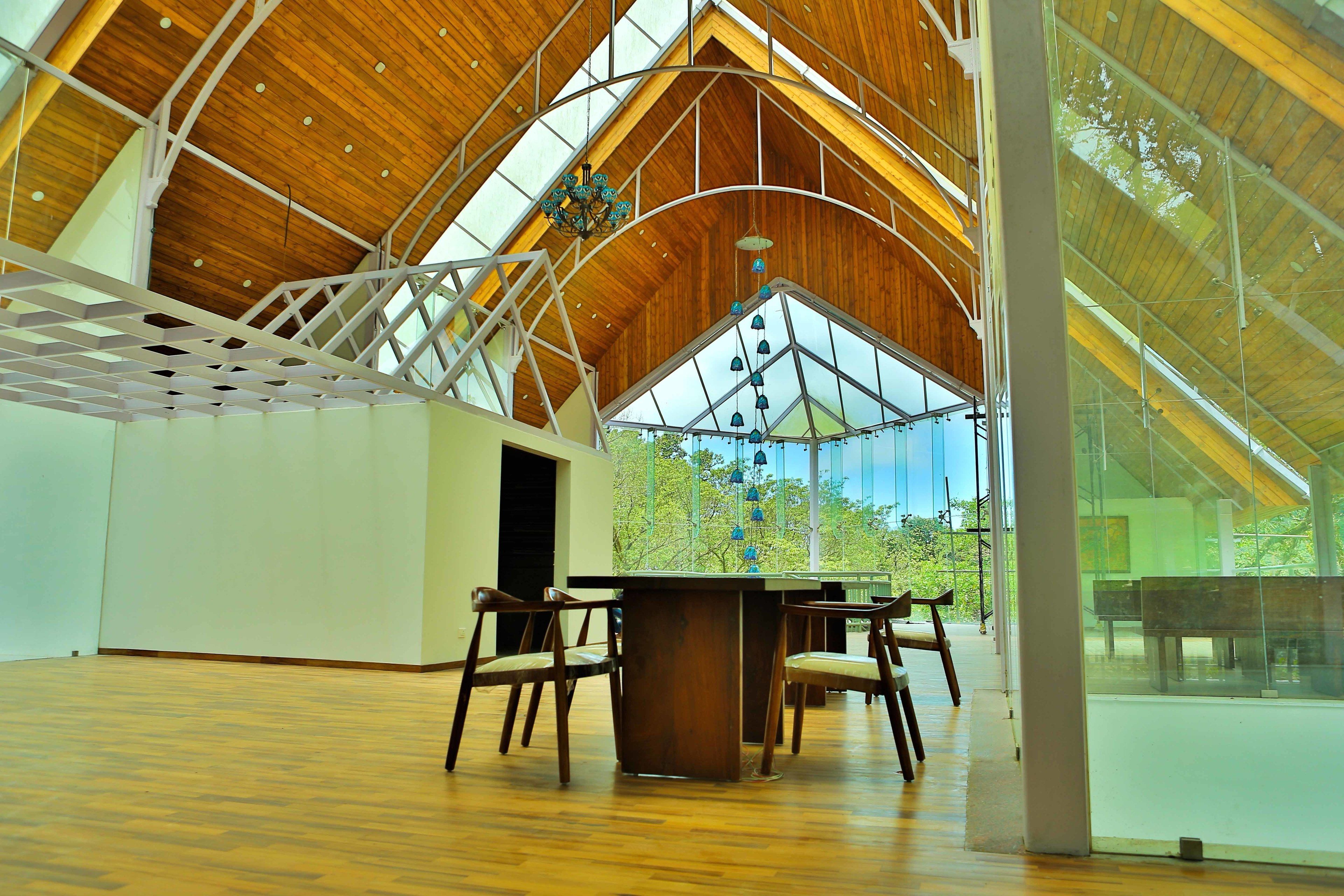 A spacious interior with a high wooden ceiling, a glass wall, and a wooden table with chairs.