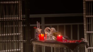 Una mesa con velas, un vaso de agua y un adorno en un balcón.
