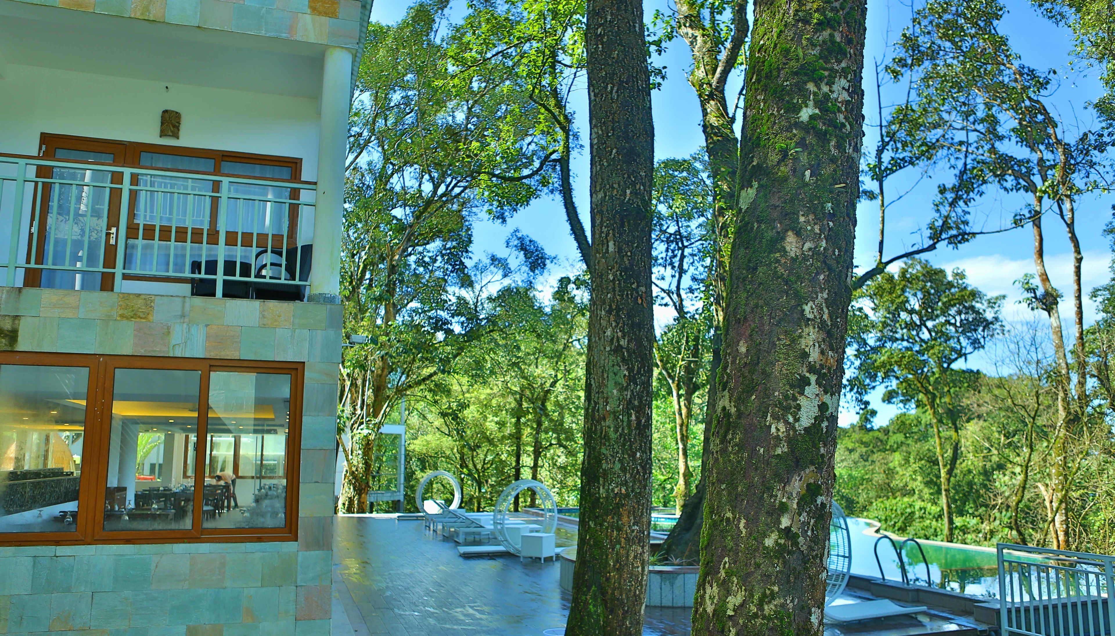 Un edificio moderno con fachada de vidrio, zona de estar al aire libre y piscina.
