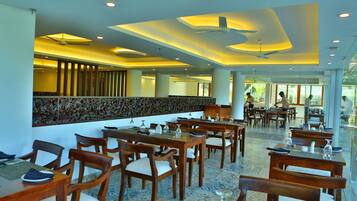 A spacious dining area with wooden tables and chairs, a decorative wall, and a ceiling fan.