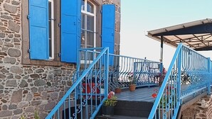 A stone building with blue shutters and a blue metal staircase leading to a covered area. - Bergama Tas Konak (Bergama)