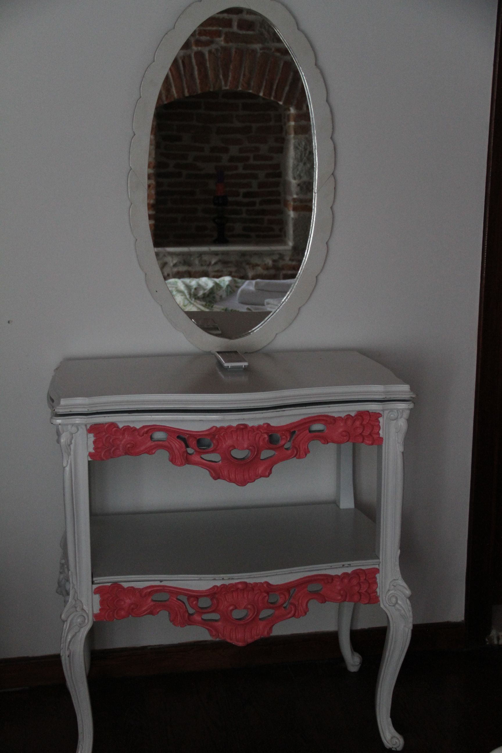 A white vanity with a mirror and red decorative trim.