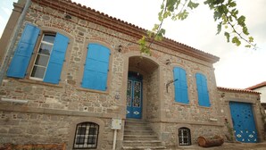 A stone building with blue shutters, a central door, and a small staircase leading to the entrance. - Bergama Tas Konak (Bergama)