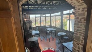 An outdoor patio area with tables and chairs, a brick wall, and a view of the cityscape. - Bergama Tas Konak (Bergama)