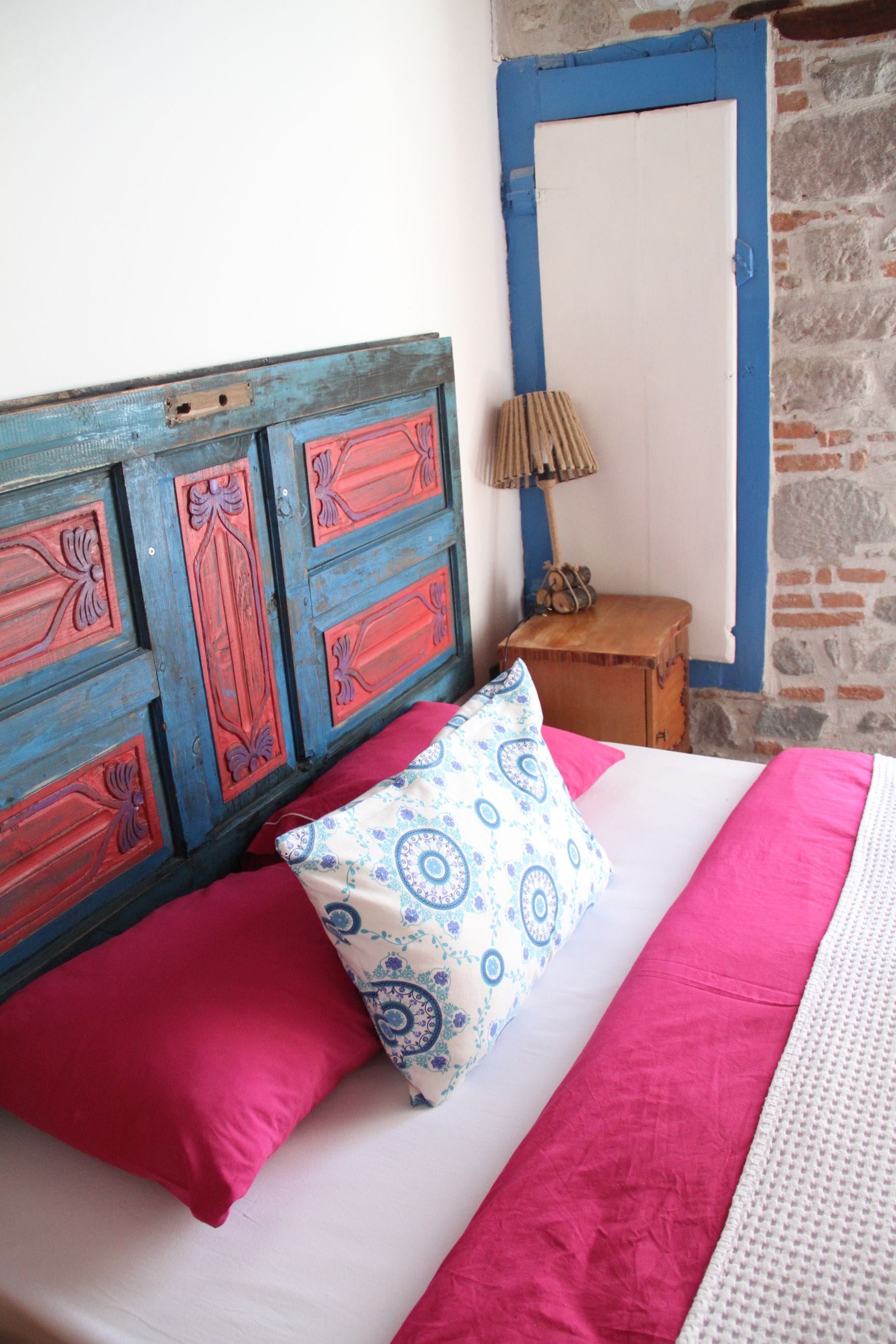 A bed with red and white bedding, a patterned pillow, and a wooden headboard.