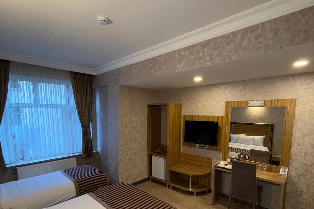 A hotel room with a bed, a desk, a television, and a small refrigerator.