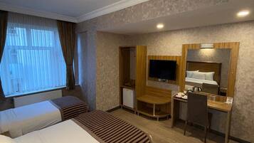 A hotel room with a bed, a desk, a television, and a small refrigerator.