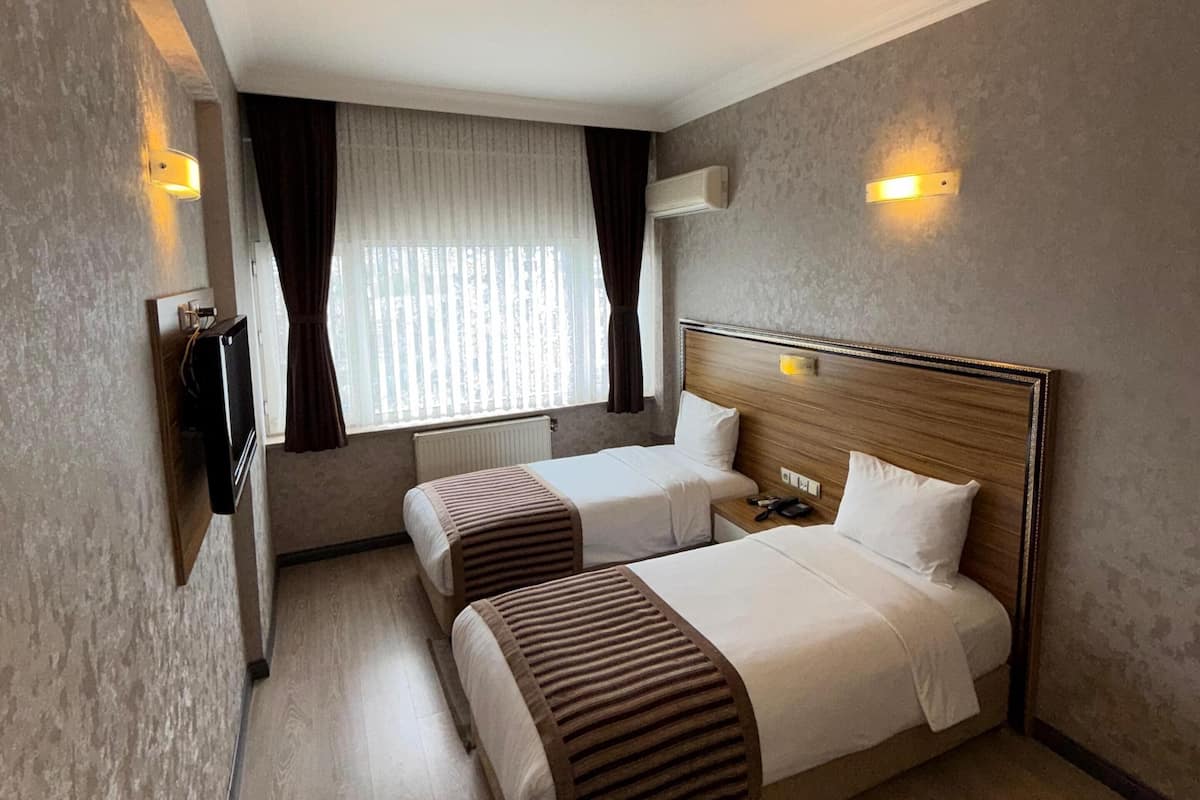 A hotel room with two beds, a TV, a desk, and a chair.