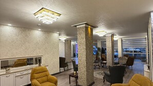 A modern interior with a central seating area, a dining table, and a view of the outside. - Buyuk Hotel (Kayseri)