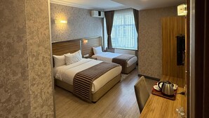 A hotel room with a large bed, a smaller bed, a desk with a kettle, and a window with curtains. - Buyuk Hotel (Kayseri)