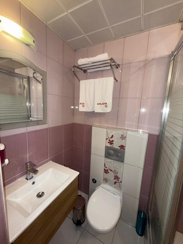 Un baño con lavamanos, inodoro y un perchero con dos toallas.