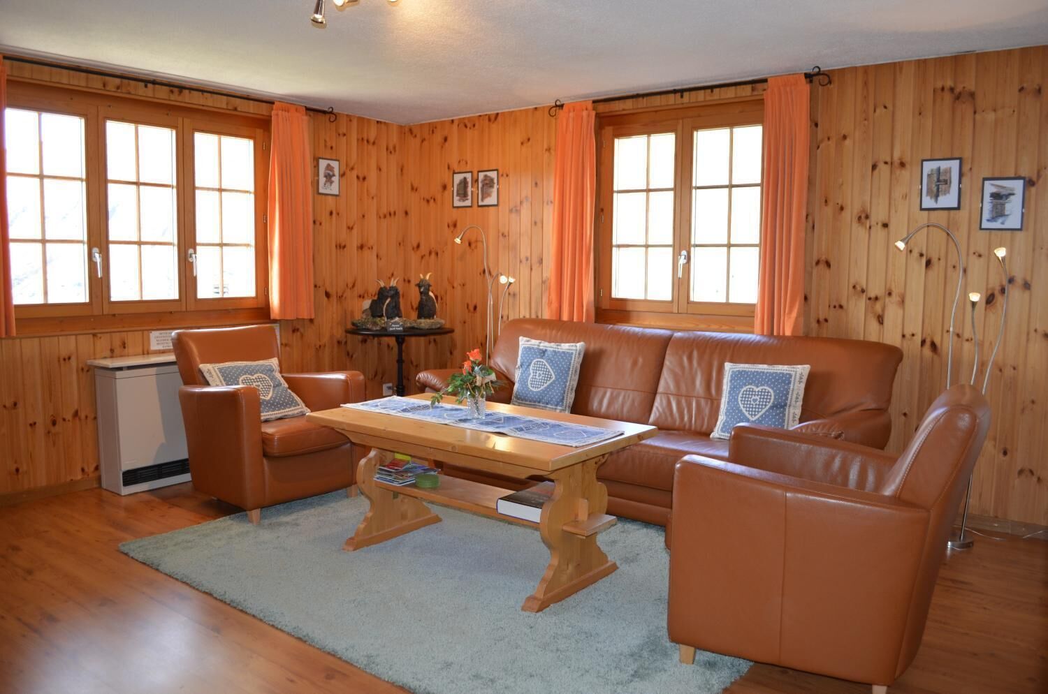 A cozy room with a wooden interior, a sofa set, a small table, and a desk.
