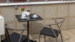 A balcony with a table and two chairs, overlooking a cityscape.